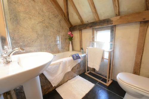 a bathroom with a sink and a tub and a toilet at Yew Tree Farm Barn, Worlingworth in Worlingworth