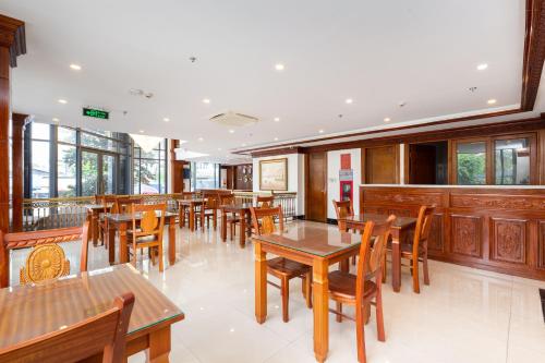 a restaurant with wooden tables and chairs and windows at Silk Hong Ha airport hotel in Ho Chi Minh City