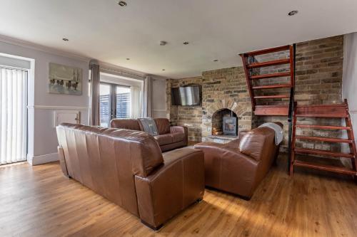 a living room with leather furniture and a brick fireplace at Hill Top in Bradford
