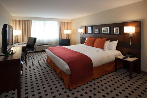 um quarto de hotel com uma cama grande e uma televisão em Penn Harris Hotel Harrisburg, Trademark by Wyndham em Harrisburg