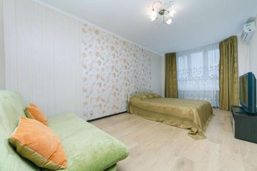 ein Schlafzimmer mit einem Bett, einem Sofa und einem TV in der Unterkunft Apartment on Akhmatovoyi 32/18 in Kiew