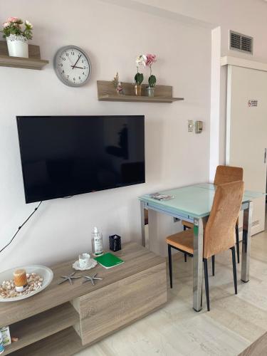 a living room with a table and a tv on a wall at Sunrise pearl in Attika Riviera apt and Parking in Rafina