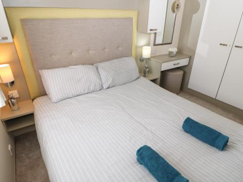 1 cama blanca grande con 2 almohadas azules. en Lushness Lodge en Morpeth