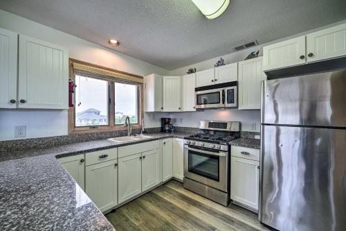 a kitchen with white cabinets and a stainless steel refrigerator at Avon Home on the Channel with Hot Tub and Deck! in Avon