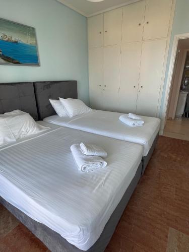 two beds in a room with white sheets and towels at Sunrise pearl in Attika Riviera apt and Parking in Rafina