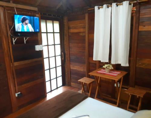 sala de estar con TV y mesa con sidx de mesa en Pousada Recanto Afetivo en Trindade