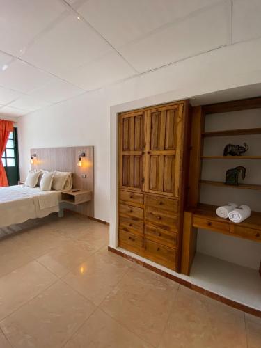 a bedroom with a bed and a wooden cabinet at Hotel Paso Realce in Guaduas
