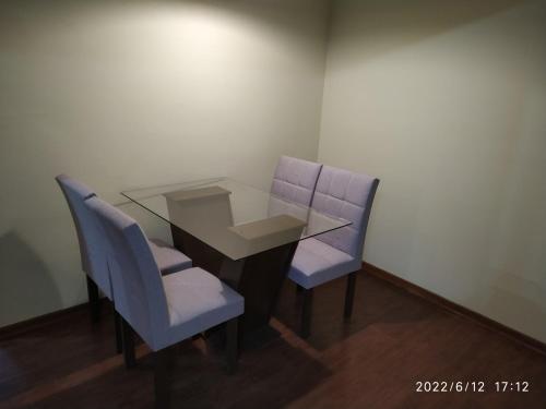 een glazen tafel en twee blauwe stoelen in een kamer bij Apto em Curitiba perto de tudo in Curitiba