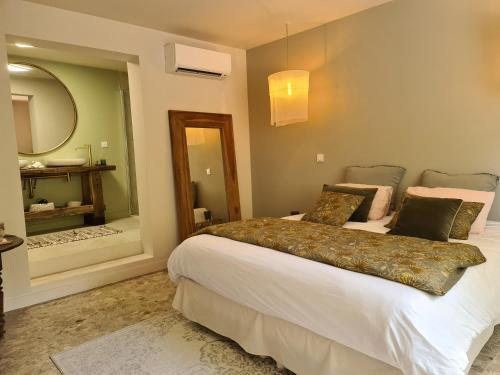 a bedroom with a large bed and a mirror at La Maison de Lyna - Suites de charme intra-muros avec parking & autonomie in Aigues-Mortes