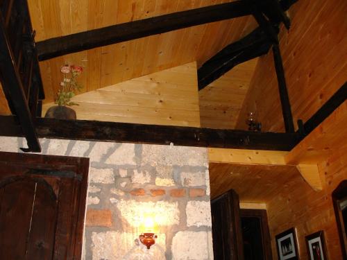 a wooden ceiling in a room with a stone wall at Zeleni Čardaci etno apartmani in Kaludjerske Bare