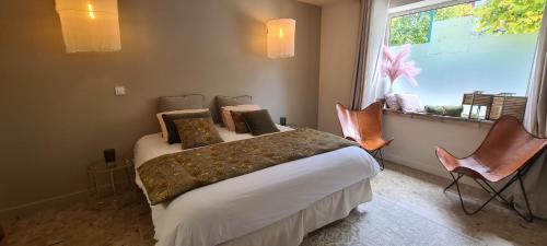 a bedroom with a bed with two chairs and a window at La Maison de Lyna - Suites de charme intra-muros avec parking & autonomie in Aigues-Mortes