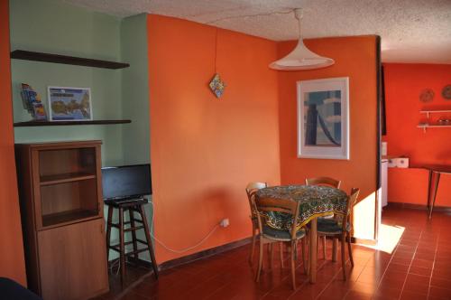 una sala da pranzo con pareti arancioni e tavolo e sedie di Cotetonda - Appartamento Taccola a Marciana Marina