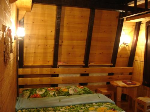 a room with a bed and a wooden wall at Zeleni Čardaci etno apartmani in Kaludjerske Bare