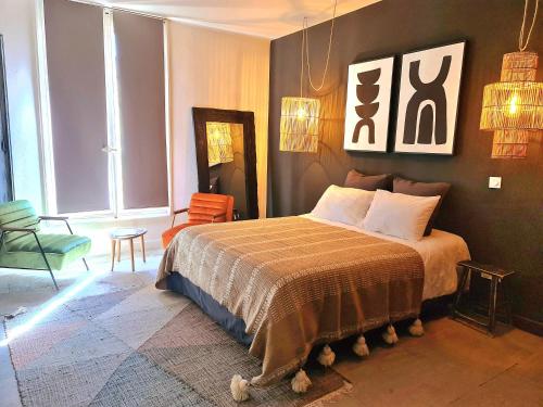 a bedroom with a bed and a chair in it at La Maison de Lyna - Suites de charme intra-muros avec parking & autonomie in Aigues-Mortes