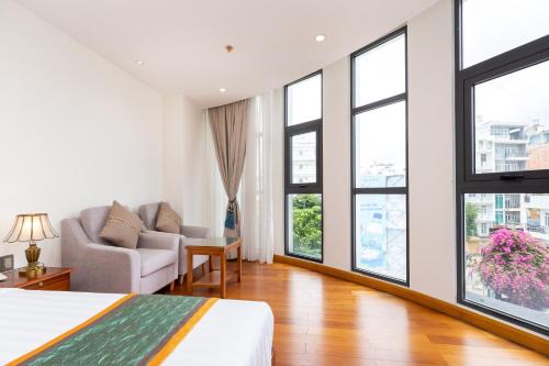 a bedroom with a bed and a couch and windows at Silk Hong Ha airport hotel in Ho Chi Minh City