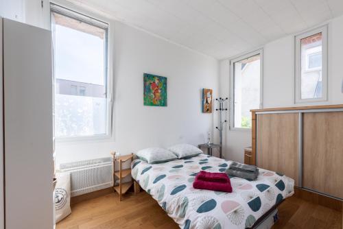 ein Schlafzimmer mit einem Bett und zwei Fenstern in der Unterkunft La Castine in Saint-Cast-le-Guildo