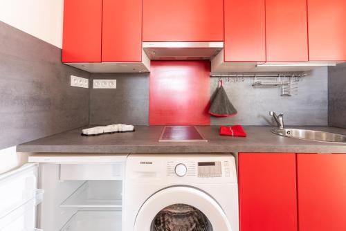 eine Küche mit roten Schränken und einer Waschmaschine in der Unterkunft La Castine in Saint-Cast-le-Guildo