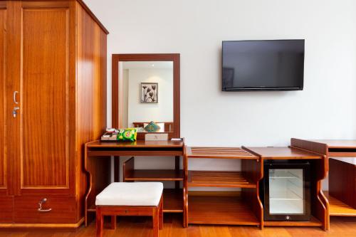a room with a desk and a tv on a wall at Silk Hong Ha airport hotel in Ho Chi Minh City
