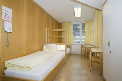um pequeno quarto com uma cama e uma mesa em Kolpinghaus Innsbruck em Innsbruck