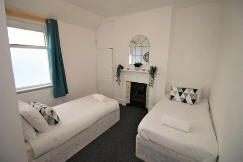 een witte kamer met 2 bedden en een open haard bij Large Modern House by Property Promise in Cardiff