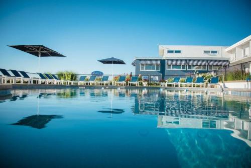 uma piscina de água com cadeiras e guarda-sóis em Atlantis Oceanfront Inn Gloucester em Gloucester