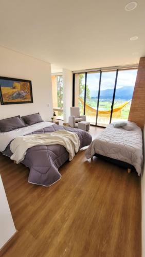 a large bedroom with two beds and a large window at Casa de ensueño Alto Turmequé a 5 min de Tibasosa in Tibasosa