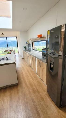 a kitchen with a stainless steel refrigerator and wooden floors at Casa de ensueño Alto Turmequé a 5 min de Tibasosa in Tibasosa