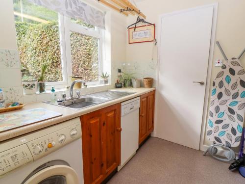 uma cozinha com um lavatório e uma máquina de lavar roupa em The Gables em Stroud