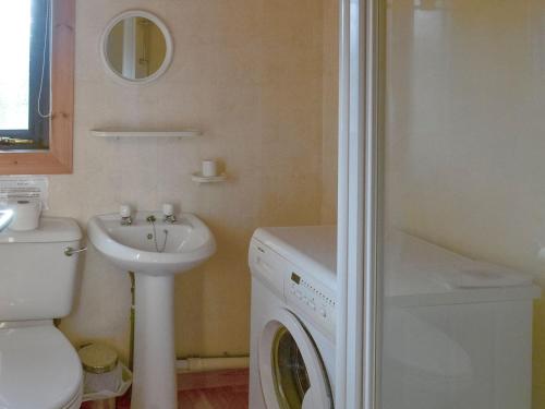 a bathroom with a washing machine and a sink at The Retreat in Woolfardisworthy