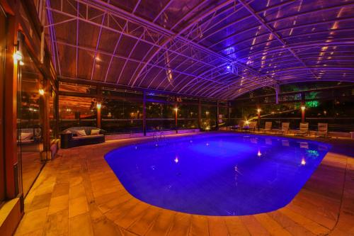 a large swimming pool in a building with a roof at Esquilo Hotel in Monte Verde