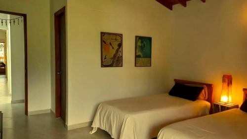 a bedroom with two beds and a hallway with a lamp at La Casa Amarilla in Jardin