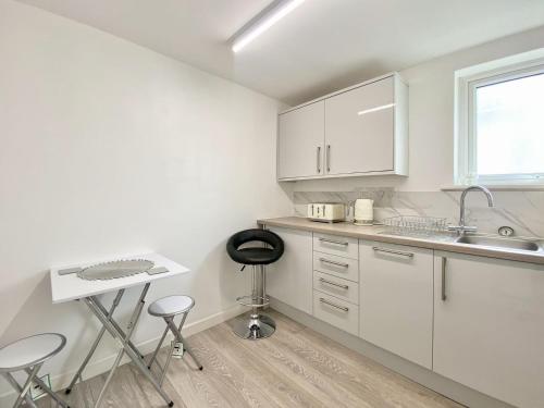 uma cozinha com armários brancos, um lavatório e um banco em Station Suite 1 - Uk40737 em North Tidworth