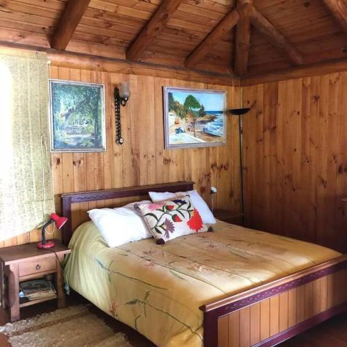 a bedroom with a bed in a wooden room at Maravillosa cabaña en orilla de Lago Vichuquén in El Rodeo