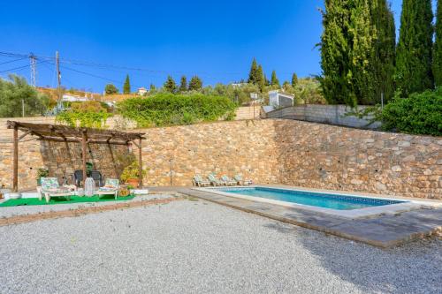 a villa with a swimming pool and a stone wall at Cortijo Montes I in Cómpeta