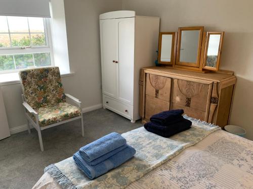 1 dormitorio con cama, silla y espejo en Sighthill Cottage, North Tolsta en Stornoway