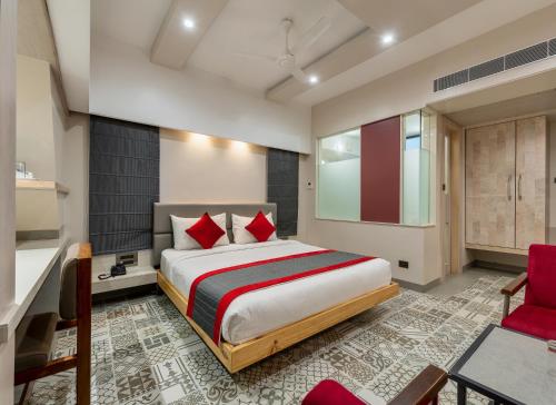a bedroom with a large bed and a red chair at Pai Resort in Belgaum