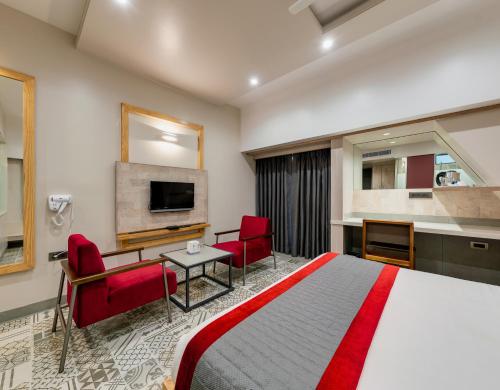 a hotel room with a bed and red chairs at Pai Resort in Belgaum
