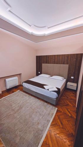 um quarto com uma cama grande e uma cabeceira em madeira em Vila Casablanca - Boutique Hotel & Restaurant em Shkodër