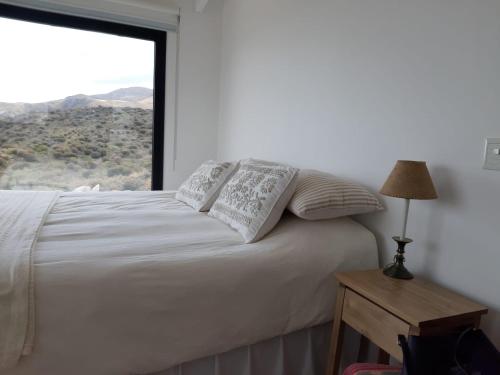 a bedroom with a white bed with a large window at Loft en Rincon de la Cumbre in La Cumbre