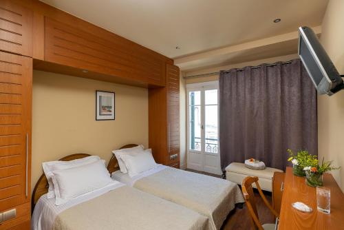 a hotel room with two beds and a television at Hotel Palladion in Ermoupoli