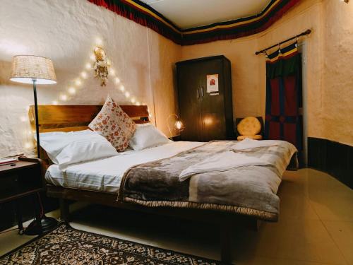 - une chambre avec un grand lit dans une pièce avec une lampe dans l'établissement Mud House Cottage & Sauna - McleodGanj, à Dharamshala