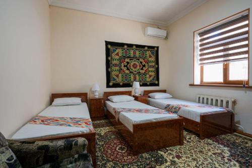 Habitación con 4 camas y ventana en Nurobod Guesthouse, en Bukhara