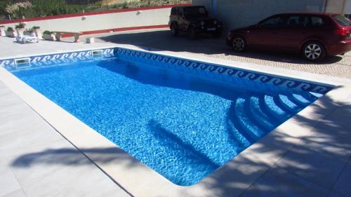 a swimming pool with blue water in a driveway at Mãe Home Foz in Foz do Arelho