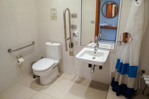 a bathroom with a toilet and a sink and a mirror at Hotel Parada Linares in Linares