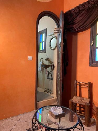 an orange room with a glass table and a mirror at Villa de l'atlas 