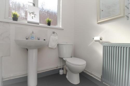 a white bathroom with a toilet and a sink at Fitzroy Terrace by Property Promise in Cardiff