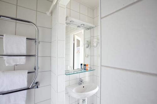 a white bathroom with a sink and a mirror at Ronnums Herrgård in Vargön