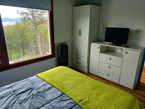 um quarto com uma cama, uma televisão e uma janela em Cálida casa en el fin del mundo em Ushuaia