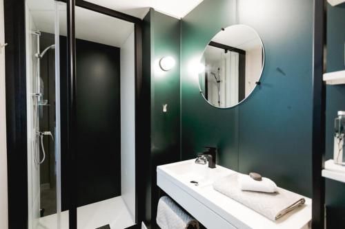 a green bathroom with a sink and a mirror at Le Valserine - Camping éco responsable in Chézery-Forens