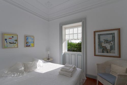 a white bedroom with a bed and a window at Casa da Madalena do Mar in Madalena do Mar
